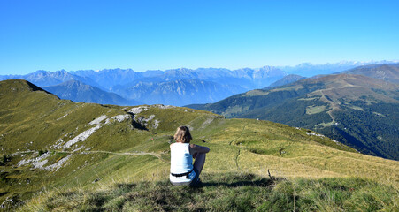 Woman overlooking mountains and the Alps from Monte Guglielmo. Lago d'Iseo, Brescia, Lombardy, Italy.