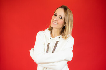 Portrait of a pretty young woman in white sweater hugging herself. Concept of selfish emotion.