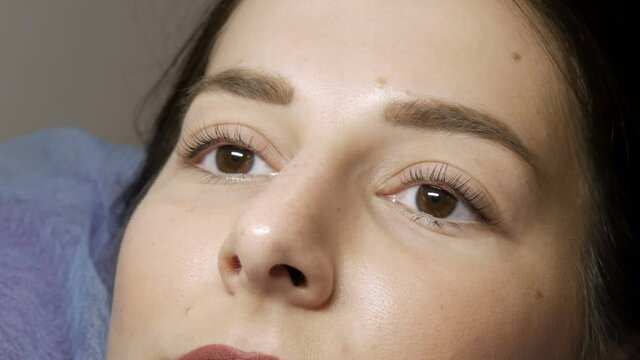 The face of a young girl before a modern eyelash lamination procedure in a professional beauty salon before the eyelash curling procedure. Portrait of a woman without makeup with dark lipstick.