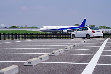 滑走路脇の駐車場と滑走を始めるジェット旅客機