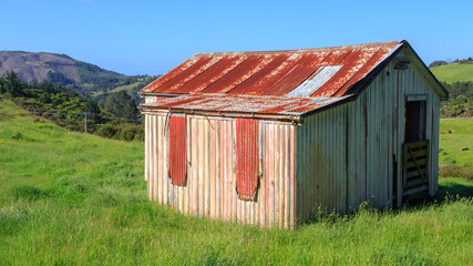 Old, rustic corrugated iron and wooden barn on a farm in New Zealand hill country