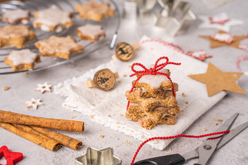 Zimtsterne Gebäck als Geschenk mit Schleife auf einem Küchentisch mit Zimtstangen, Ausstechformen und Deko