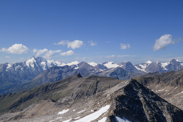 Obraz premium Panoramic view from top of Hohe Sonnblick in Austrian Alps on Gro?glockner. The whole area is very steep and dangerous, with many lose stones. Many mountain chains in the back. Sunny day. Expedition
