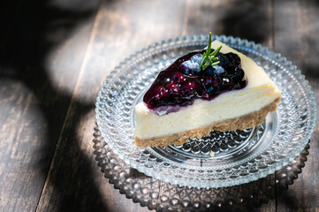 A Blueberry cheesecake on wooden table. Blueberry Cheesecake is thick, creamy and topped with a homemade blueberry sauce.