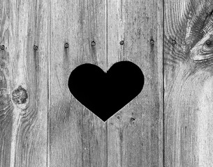 Fototapeta na wymiar Heart Shape on old weathered wooden outhouse door. Perfect symbol for love that is weathered but ages well! Beautiful aged grey wood texture / pattern