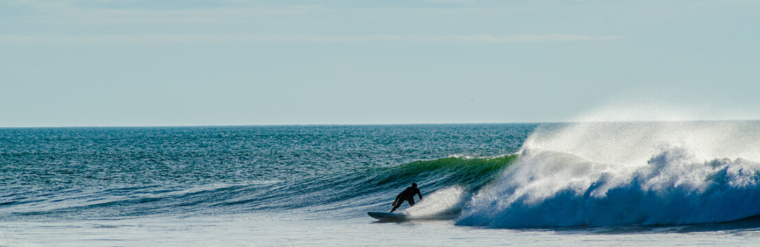 Vendée, France; November 29, 2020: from the Sauzaie spot, a black silhouette of a surfer on the point break, Bretignolles Sur Mer.

