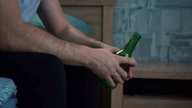 man's hands holding a bottle of beer