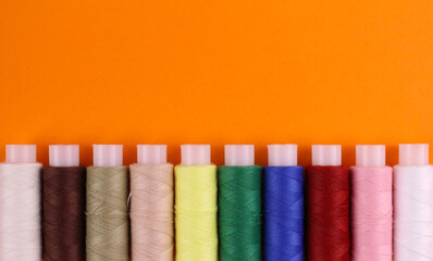 Multicolored threads from below orange background
