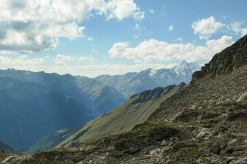 Fototapeta na wymiar Panoramic view from Hohe Sonnblick in Austrian Alps on Gro?glockner. The whole area is very steep and dangerous, with many lose stones. Green, steep meadows in front. Sunny day. Expedition