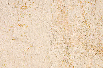 Grunge background of cracked peeling walls with peeled putty in beige tones