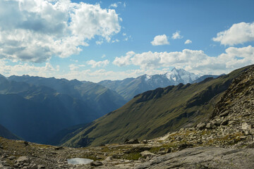 Obraz premium Panoramic view from Hohe Sonnblick in Austrian Alps on Gro?glockner. The whole area is very steep and dangerous, with many lose stones. Green, steep meadows in front. Sunny day. Expedition