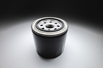 Black new oil filter in contrasting light on a black and white background. Wide angle