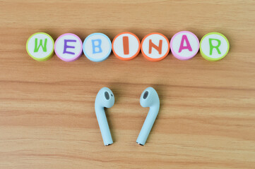 Top view of earphones and alphabet erasers with text WEBINAR. Business and education concept.