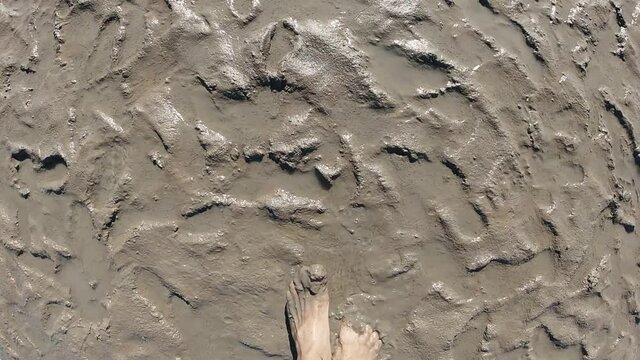 A man walks with bare feet along the shore of the Wadden Sea. POV Slow motion