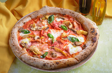 Capricciosa pizza with cheese, bacon and tomatoes and basil, italian meal