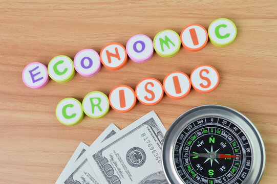 Selective focus of compass, money banknotes and alphabet erasers with text ECONOMIC CRISIS. Business concept.