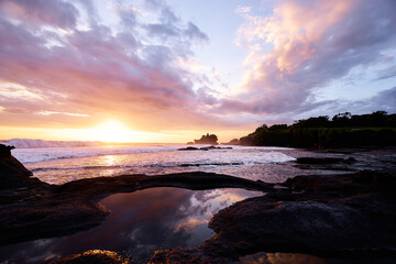 Beautiful balinese landscape. Ancient hinduism temple Tanah lot on the rock against sunset sky. Bali Island, Indonesia.