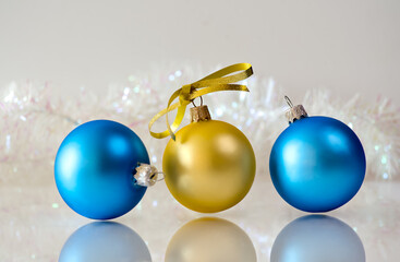 Blue and golden Christmas balls with ribbon bow on white reflective surface