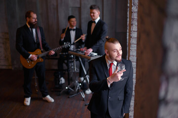 Party with music band. Group of handsome young man wearing tuxedo.