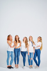 Fototapeta premium Your tex here. Group of amazed young women looking up on copy space on white background.