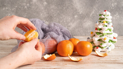 Fototapeta na wymiar Hand peeling ripe sweet mandarine. Preparing for Christmas time and winter holidays at home concept