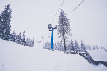 Ski lift with seats going over the mountain and paths from skies and snowboards.