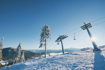 Ski lift with seats going over the mountain and paths from skies and snowboards. Beautiful winter...