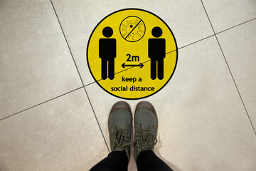 Keep social distance as preventive measure during coronavirus outbreak. Yellow warning sign on...