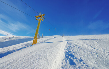 Ski lift going over the snowy mountain and paths from skies and snowboards.