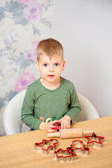 A young boy is getting ready for Christmas. Gingerbread baking