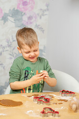 A young boy is getting ready for Christmas. Press the shapes of gingerbread.