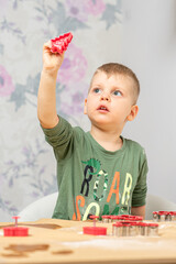 A young boy holds the gingerbread shape in his hand, holding out against the light.
