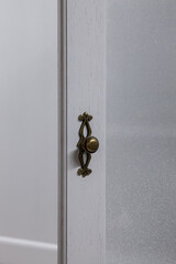 Close-up of white wooden kitchen cabinet door handle.
