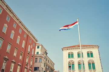 National croatian flag against sky. Beautiful cityscape postcard with Split town architecture.