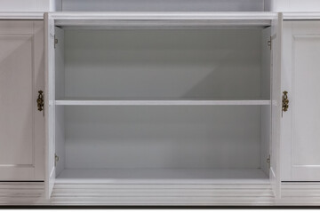 Open doors of a white wooden kitchen cabinet. Close-up of empty kitchen cabinet shelves.