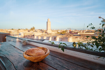 Traditional morrocan bread on wooden table in cafe. View of Marrakesh Old Town from the cafe terrace. Marrakech Medina, Morocco, Africa.