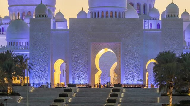 Sheikh Zayed Grand Mosque with stairs in Abu Dhabi day to night transition timelapse after sunset, UAE. Evening view from Wahat Al Karama