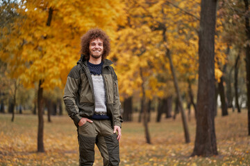 Fototapeta na wymiar Outdoors portrait of young man with curly hair in the park.