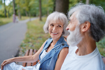 Senior family couple sitting together on bench at summer park.