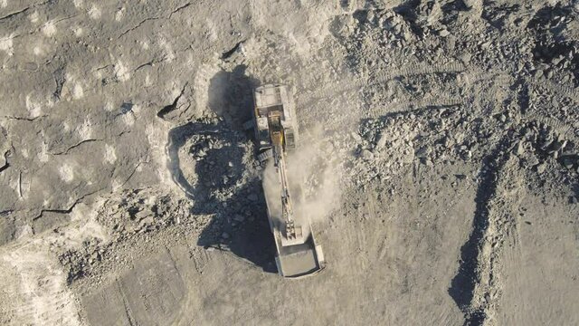 Excavator loads mineral into mining truck. Open pit mine, extractive industry, top view aerial drone. High quality 4k footage