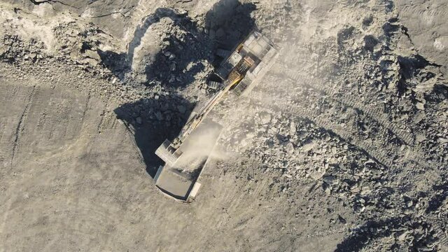 Excavator loads mineral into mining truck. Open pit mine, extractive industry, top view aerial drone. High quality 4k footage