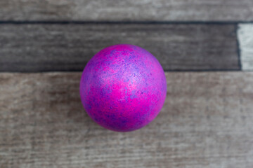 Colored Easter egg on wooden background, top view