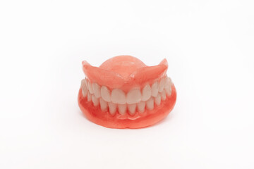 Full removable plastic denture of the jaws. Set of dentures on a white background. Two acrylic dentures. Upper and lower jaws with fake teeth. Dentures or false teeth, close-up. Copy space