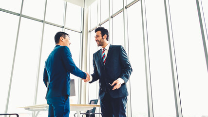 Business people handshake in corporate office showing professional agreement on a financial deal...