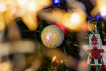 Interesting Christmas toys on the Christmas tree. Christmas accessories in white, among flashing lanterns and lights. Festive and elegant cute things for family holidays.