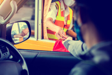 Selective focus to hand of driver pay for the expressway. Blurry image of drivers and cashiers wear face masks to prevent the spread of the Coronavirus (Covid-19).