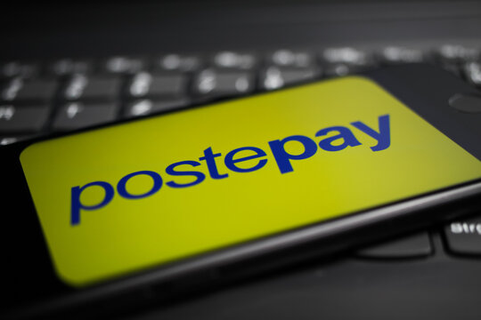 Viersen, Germany - April 9. 2020: Close up of mobile phone screen with logo lettering of postepay  payment provider on computer keyboard (selective focus on letter e)