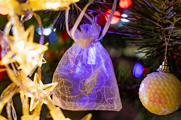 Interesting Christmas toys on the Christmas tree. Christmas accessories in white, among flashing lanterns and lights. Festive and elegant cute things for family holidays.