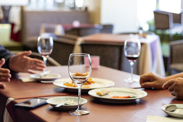 wineglass, potato wedges, spring rolls on a dark-red table at end of a party.