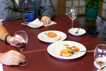 wineglass, potato wedges, spring rolls on a dark-red table at end of a party.